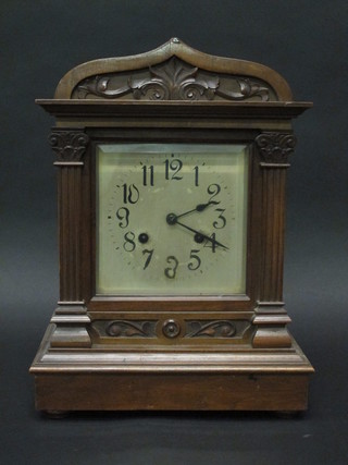 An Edwardian striking bracket clock with square silvered dial and Arabic numerals contained in an arch carved walnut case 11"