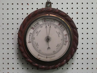 An Edwardian aneroid barometer with enamelled dial contained  in a carved oak case 9"