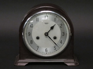 An Art Deco chiming mantel clock with silvered dial and Arabic numerals contained in an arched brown Bakelite case 9"