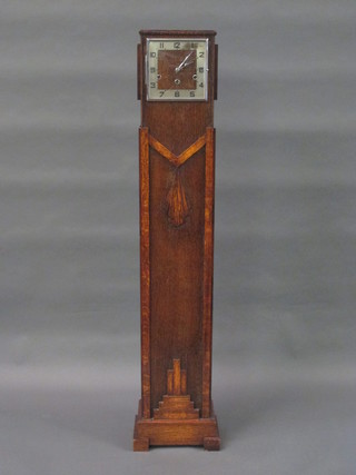 An Art Deco 8 day striking Granddaughter clock with square  dial, chapter ring and Arabic numerals contained in an oak case  53"
