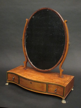 A Georgian mahogany oval plate dressing table mirror contained  in a mahogany swing frame, the base of serpentine outline with  crossbanded top, fitted 1 long and 2 short drawers, raised on gilt  paw supports 18 1/2"
