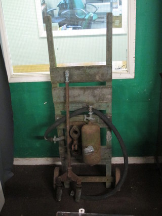 A portable metal fire pump raised on a wooden stillage with iron wheels