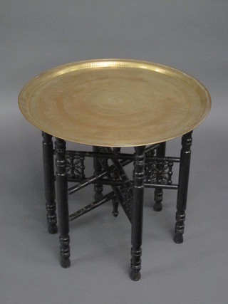 A circular Benares brass tray raised on a turned folding ebonised  stand 23"