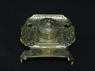 A Victorian brass inkwell with hinged lid complete with china liner