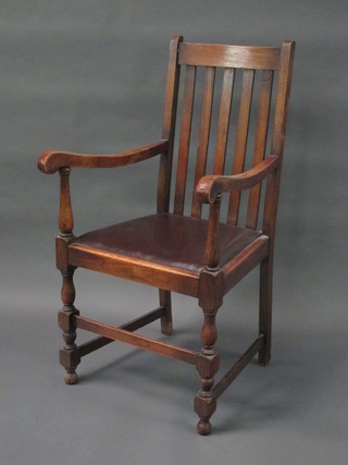 An oak stick and rail back carver chair with upholstered drop in seat, raised on turned and block supports