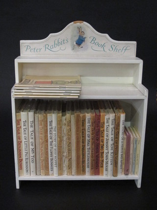 2 various editions of Peter Rabbit books contained in a wooden shelf