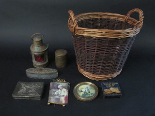 A circular twin handled basket containing 2 easel photograph frames, a reproduction port lantern etc