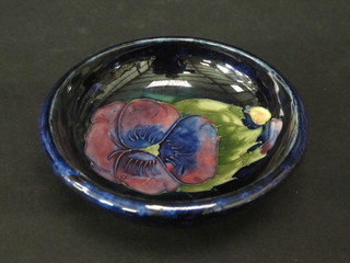 A circular Moorcroft blue glazed bowl decorated a pansy, the base marked W Moorcroft Potter to the Queen 4 1/2"