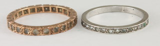 A gold eternity ring set white stones and a silver eternity ring