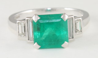 An 18ct white gold dress ring set a square emerald and with baguette cut diamonds to the shoulders  ILLUSTRATED