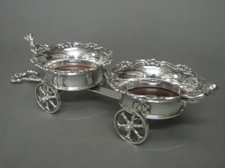 A pair of silver plated wine coolers raised on a carriage