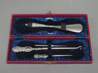 A silver handled shoe horn, a button hook and 1 other implement  case
