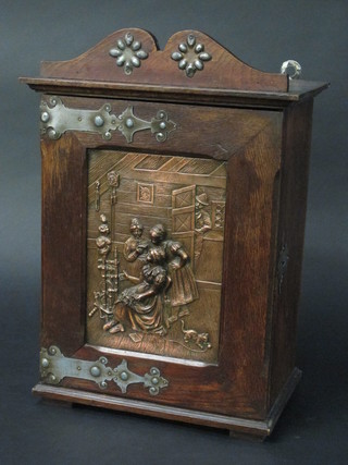 A Continental oak hanging cabinet enclosed by a panelled door  set an embossed copper plaque with interior scene 12"