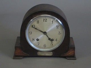 A 1930's striking mantel clock with silvered dial and Arabic  numerals contained in an arch shaped oak case