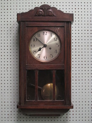 A striking wall clock with silvered dial and Arabic numerals contained in an oak case
