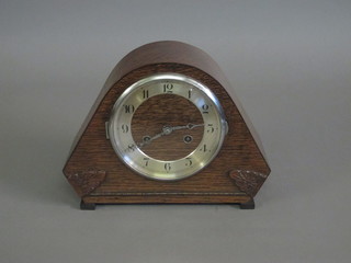 An Art Deco 8 day striking mantel clock with silvered dial and Arabic numerals contained in an arch shaped oak case