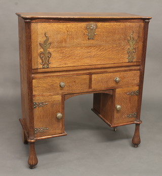 A Continental Art Nouveau oak student's bureau with fall front revealing a fitted interior above 1 long and 2 short drawers and  double cupboard beneath, raised on bun feet 36"