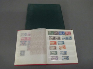 A green album of first day covers and a red stock book of stamps