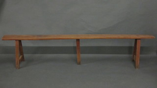 A rectangular fruitwood bench raised on trestle supports 87"