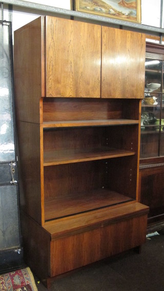 A 1960's Designer rosewood cabinet fitted a double cupboard enclosed by a panelled door above 3 shelves, the base fitted 1  long drawer 36"