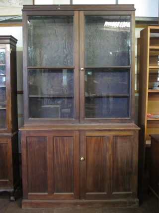 A 19th Century mahogany bookcase on cabinet the upper section  fitted shelves enclosed by glazed panelled doors, the base fitted a  cupboard enclosed by panelled doors, raised on a platform base  49"