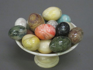 A circular carved alabaster comport and a collection of marble eggs