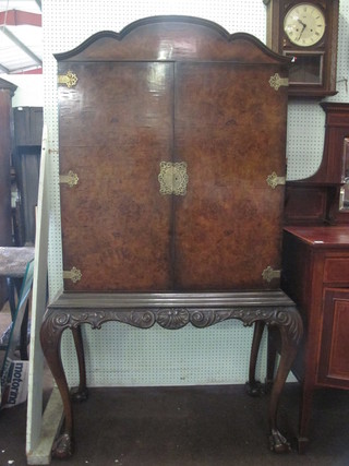 A Queen Anne style arch shaped walnut cocktail cabinet enclosed  by panelled doors, raised on cabriole supports 36"