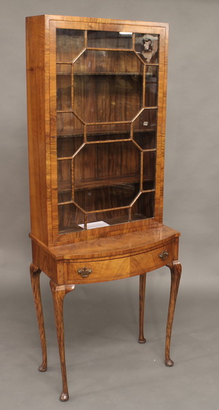 A Queen Anne style walnut display cabinet on stand, the upper section fitted shelves enclosed by astragal glazed panelled doors,  the bow front base fitted 1 long drawer, raised on cabriole  supports 24"