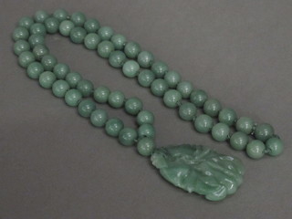 A carved green hardstone pendant hung on a string of hardstone  beads