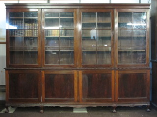 An Edwardian Chippendale style mahogany library bookcase, the  upper section with moulded cornice fitted adjustable shelves  enclosed by glazed panelled doors, the base fitted a cupboard  enclosed by panelled doors, raised on cabriole supports 96"