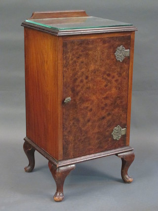 A Queen Anne style figured walnut bedside cabinet enclosed by a panelled door, raised on cabriole supports 16"