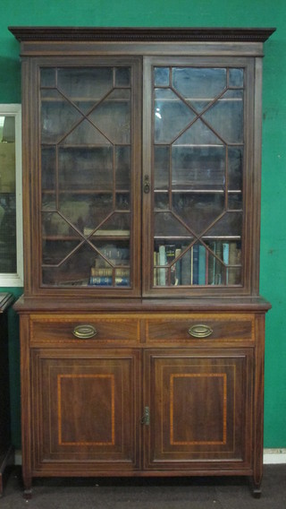 An Edwardian inlaid mahogany display cabinet, the upper section  with moulded and dentil cornice, the shelved interior enclosed by  astragal glazed panelled doors, the base fitted 2 long drawers  above a double cupboard enclosed by panelled doors, raised on  square tapering supports 48"