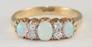 An 18ct yellow gold dress ring set 3 oval cut opals supported by 4 diamonds