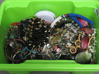A green plastic crate containing a collection of costume jewellery