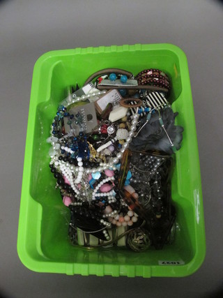 A green crate containing a collection of costume jewellery