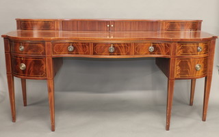 A Georgian style mahogany sideboard of serpentine outline, the upper section enclosed by a tambour shutter, the base fitted 1  long drawer flanked by 2 short drawers above a double cupboard,  raised on square tapering supports 77"