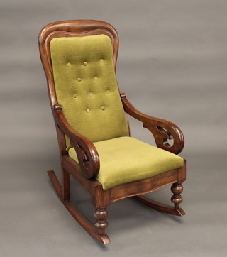 A Victorian mahogany rocking chair upholstered in green buttoned material