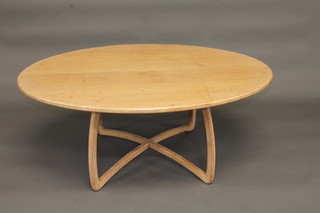 An oval light oak coffee table raised on X framed supports, the  base carved a mouse 51"