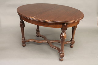 An oval extending dining table with concealed extra leaf, raised  on turned supports with X framed stretcher 47"
