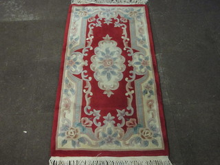A red ground and floral patterned Chinese rug 60" x 30"