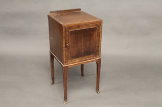 A 1930's walnut bedside cabinet enclosed by a panelled door,  raised on square tapering supports 15"