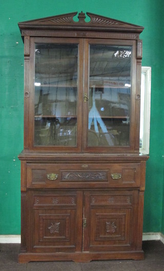 An Edwardian carved walnut secretaire bookcase, the upper section with moulded cornice, fitted adjustable shelves above a  secretaire drawer above a double cupboard enclosed by panelled  doors, raised on a platform base 48"