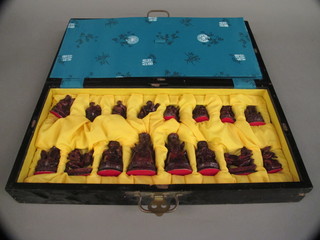 An Oriental style chess set with resin pieces complete with  folding lacquered board/box