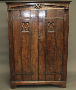 A carved oak wardrobe of panelled construction with moulded  cornice enclosed by a carved panelled door 50"