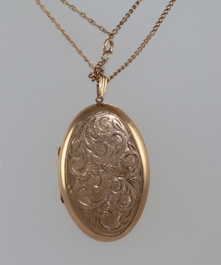 A 9ct engraved oval gold pendant hung on a gilt chain
