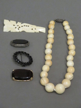 A string of ivory beads, an ivory brooch and 3 other brooches