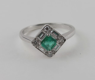 A lady's 18ct white gold dress ring set square cut emerald  supported by diamonds