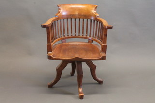 An Edwardian oak tub back revolving office chair, raised on cabriole supports