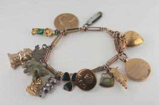 A gold charm bracelet hung a 9ct gold golf medal, a 9ct gold and enamelled shamrock pendant, a 9ct gold and enamelled crest  charm and other charms