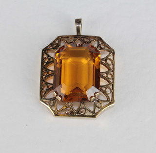 A lozenge shaped amber stone set in a gold pendant